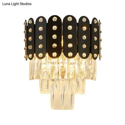 Modern black and gold 3-tiered wall-mounted light with clear faceted crystal accents and cascading glass prisms