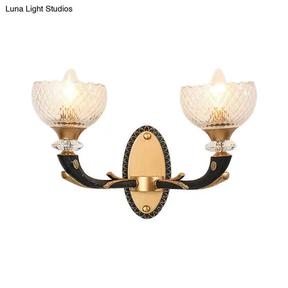 Elegant metal black sconce with gold accents and clear prismatic glass shade for modern bedroom lighting