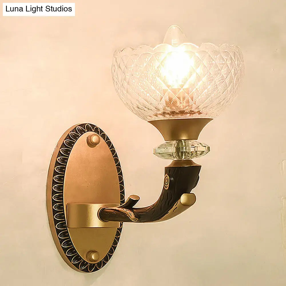 Antique brass wall sconce with metal black sconce arm and clear prismatic glass shade for modern bedroom lighting