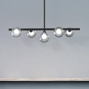 Modern black metal ceiling light with five bubble clear glass globe bulbs for a clear glass island dining room