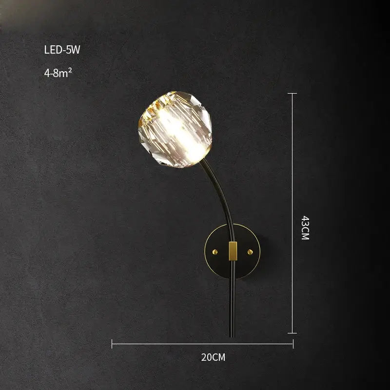 Modern black and gold wall sconce with faceted crystal led globe on curved arm and brass plate decorbites crystal led wall