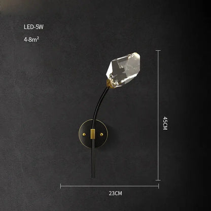 A sleek black and gold decorbites crystal led wall sconce with a faceted clear bulb for modern bedroom lighting