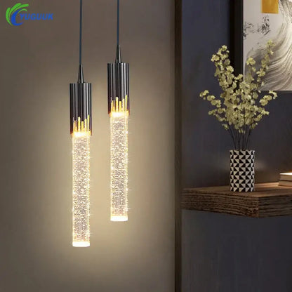 Two modern pendant lights with black cylindrical tops and golden accents featuring a crystal rod pendant for dining room