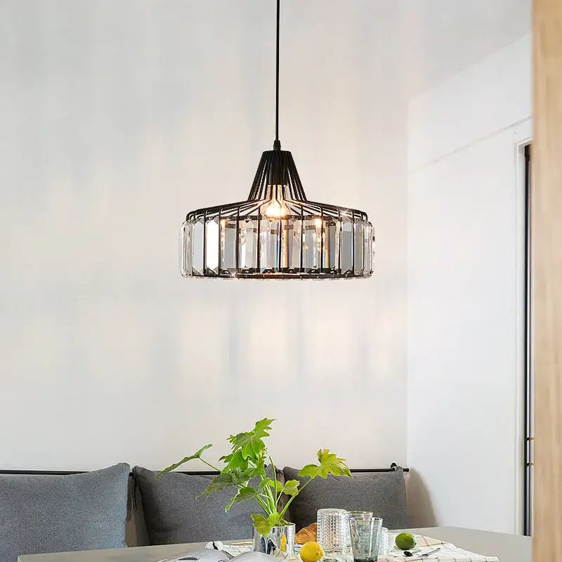 Modern black iron and gold round pendant light with clear crystal accents hanging above dining table