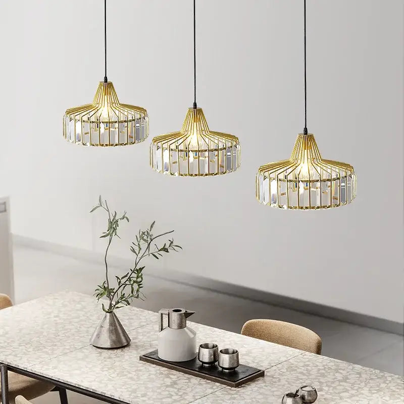 Three elegant black iron and gold round pendant lights with crystal accents hang above a dining table