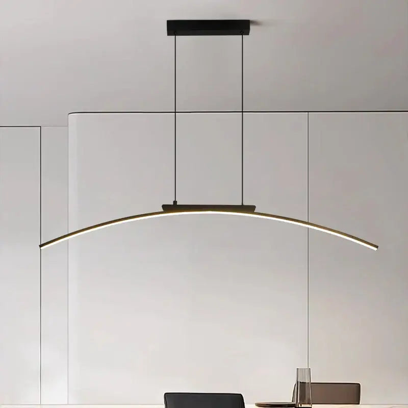 Modern black and gold curved bridge pendant light with sleek LED strip emitting warm white light for dining table