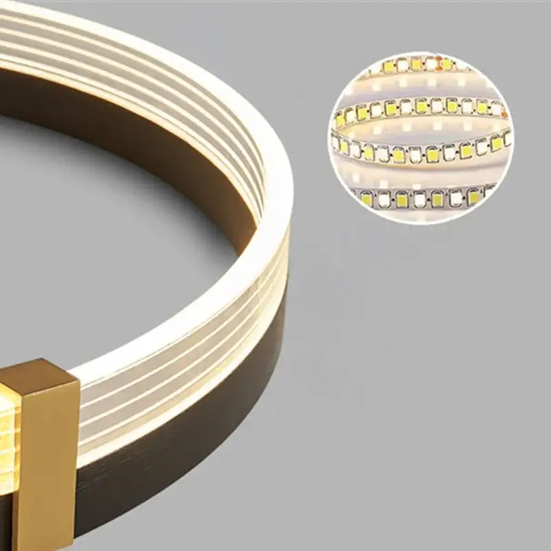 A sleek curved led strip light with warm white glow and gold end cap in modern black and gold decorbites circle chandelier