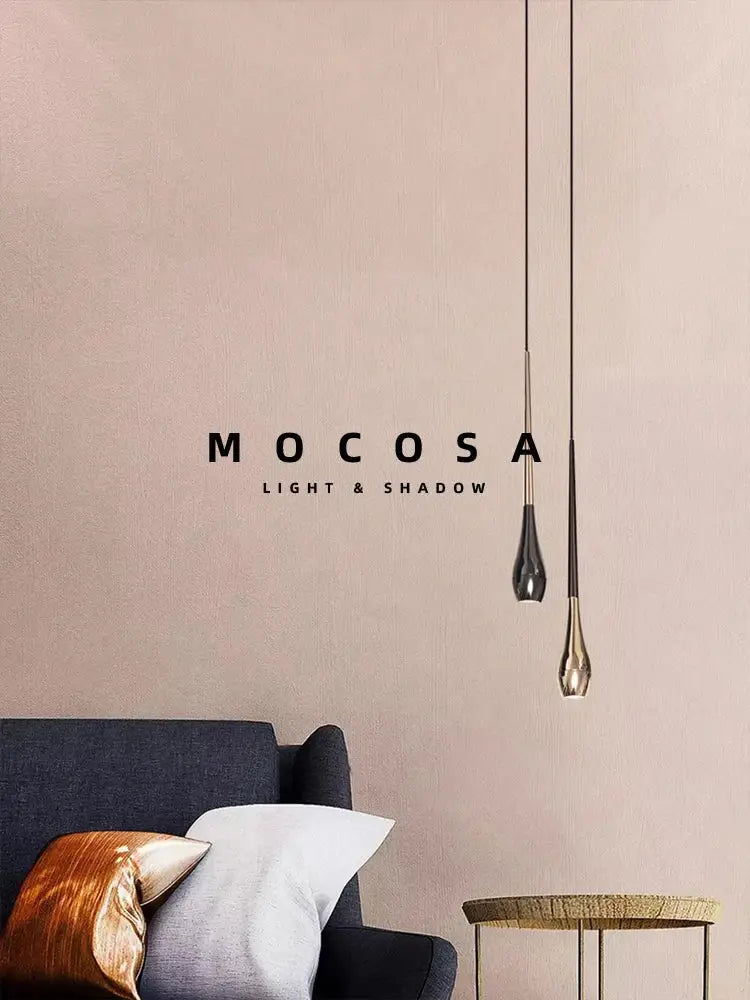 Two sleek black and gold pendant lights with metallic finish hang against a soft pink wall remote control included