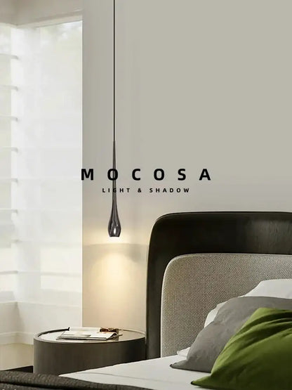 A sleek modern black and gold pendant light with metallic finish and remote control hanging in a dining room