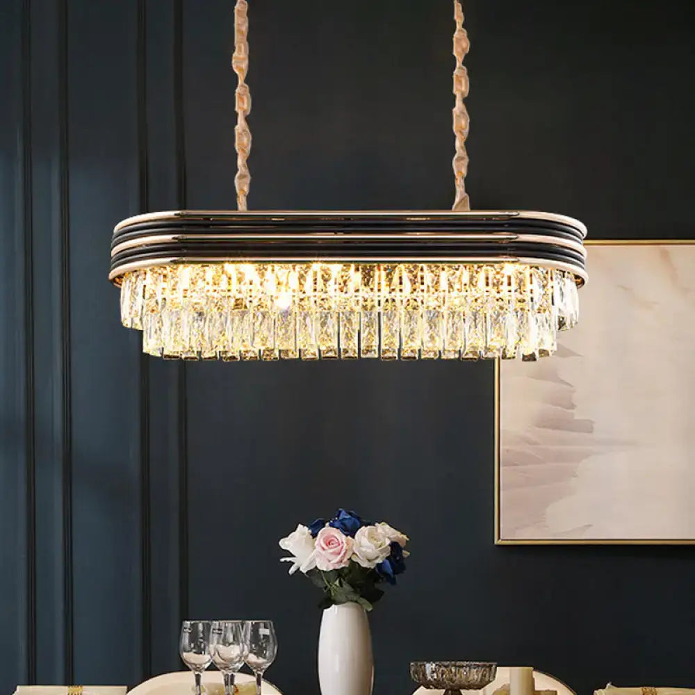 Elegant DecorBites™ elliptical pendant lamp with black and gold frame and cascading clear crystal prisms for island lighting