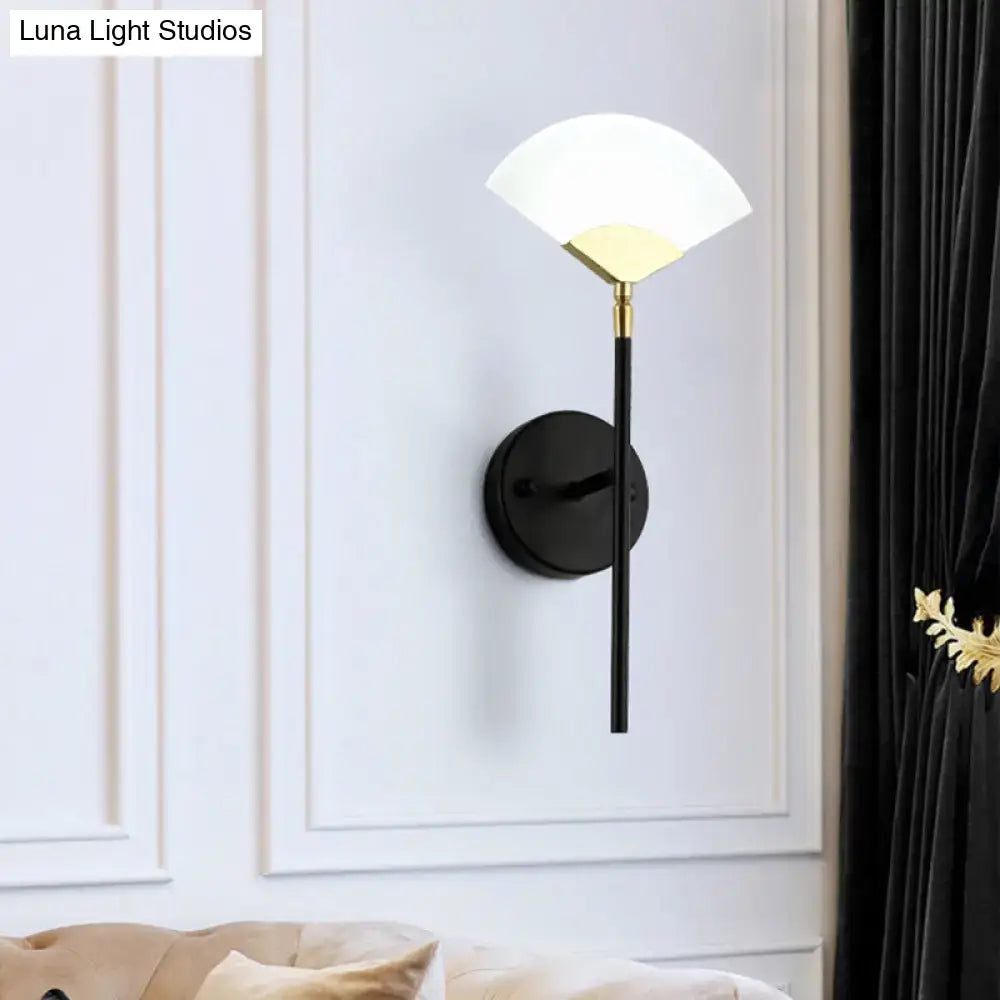 A sleek black and gold wall mount light with a frosted glass shade designed as a modern bedroom sconce
