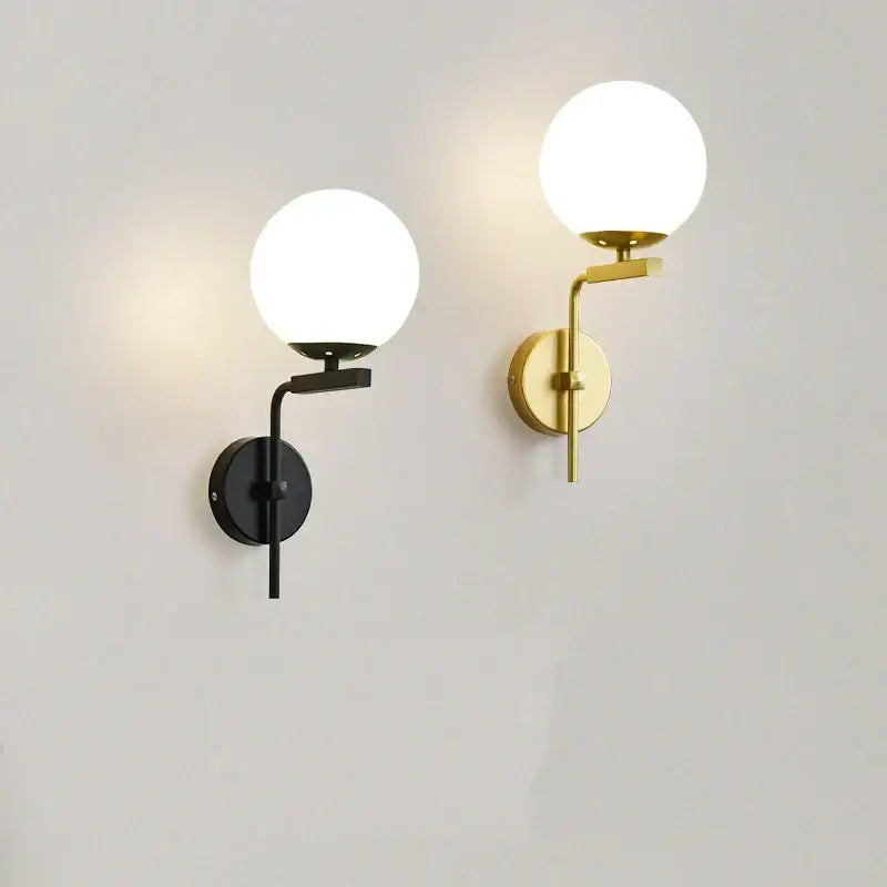 Two modern spherical wall lamps in matte black and brushed gold with frosted glass ball led globes for bedroom decorbites