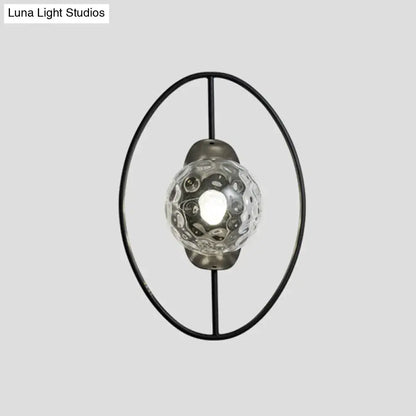 Modern black metal oval frame wall lamp with textured clear glass globe featuring intricate bubble pattern fixture type