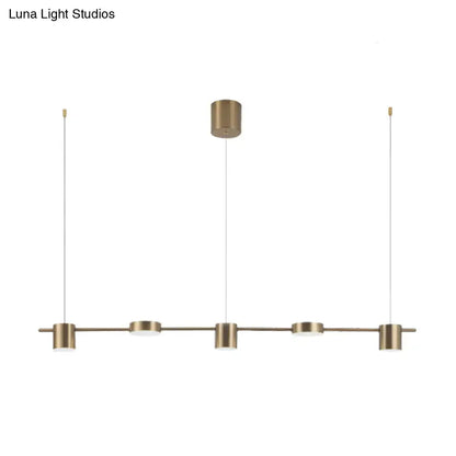 Modern black gold ceiling light fixture with brass-finished pendant and four cylindrical fixtures for kitchen island