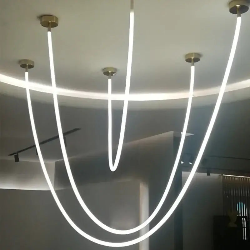 Modern black and gold linear pendant light with five curved white led light strips as a dining room light source