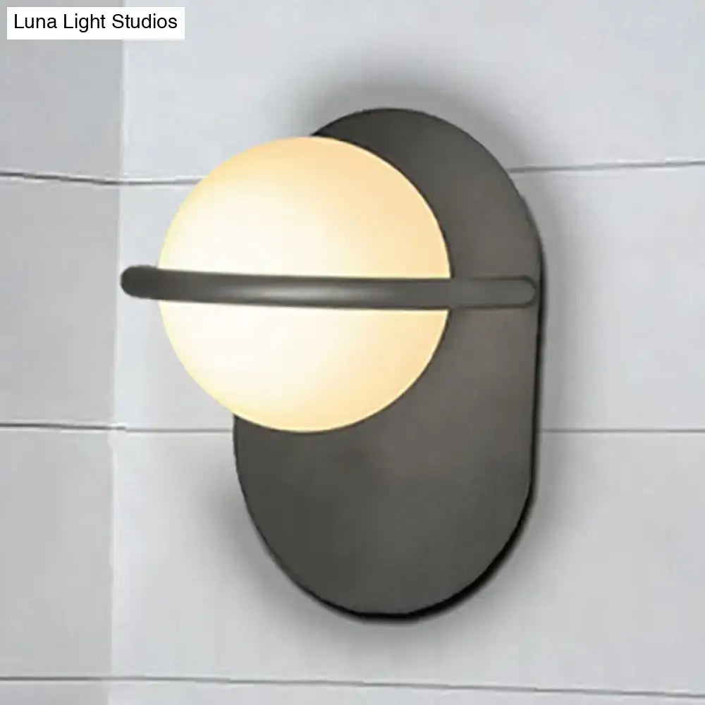 Modern black and gold wall light with matte metal backplate and warm glowing milk glass shade for bedroom use