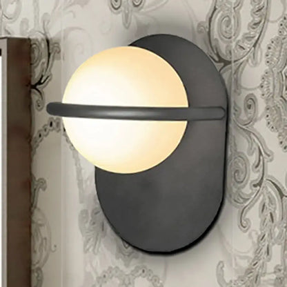 Modern black wall light with warm glowing milk glass shade and metal backplate suitable for bedroom lighting