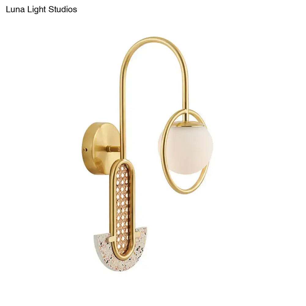 Gold-toned wall sconce with curved arm, opal glass ball shade, woven mesh panel, terrazzo base, 110v-120v and 220v-240v compatible