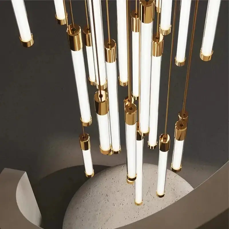 Modern black and gold pendant chandelier with multiple white cylindrical light tubes and polished steel rods for staircase lighting