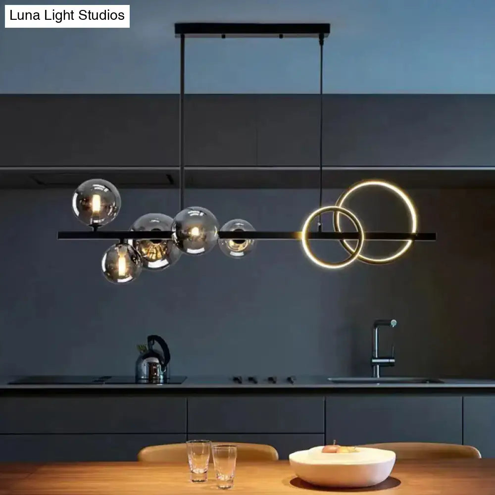 Modern black metal pendant light with clear glass spheres and glowing gold rings for dining room illumination