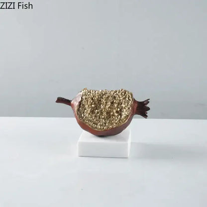 Modern black and gold pomegranate sculpture with a glossy burgundy exterior and decorbites golden glitter interior on marble base