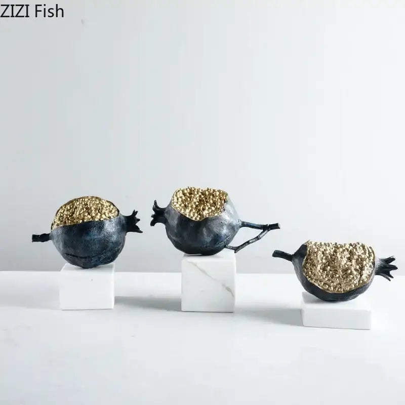 Modern black and gold pomegranate sculpture set featuring decorbites golden pomegranate figurines on white marble bases