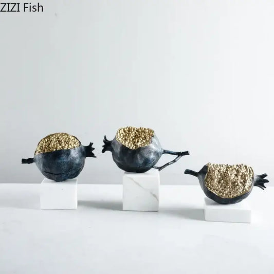 Modern black and gold pomegranate sculpture set featuring decorbites golden pomegranate figurines on white marble bases