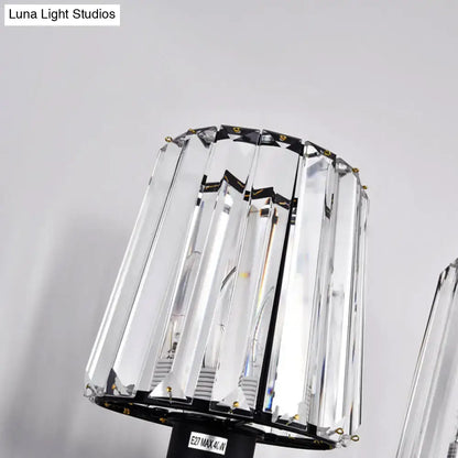 Modern black and gold wall lamp with clear glass crystal shade featuring vertical facets and black metal frame for bedroom use