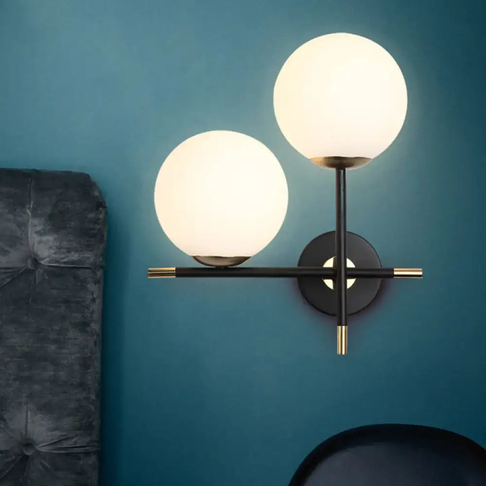Modern two-light wall light with milky glass shade black metal frame and gold-toned hardware for bedroom use