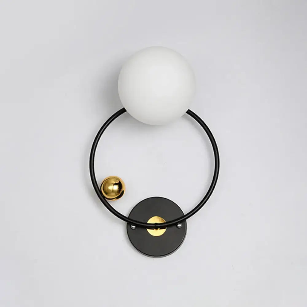 Modern black and gold wall sconce light with opal glass shade featuring a matte white spherical glass and metal frame