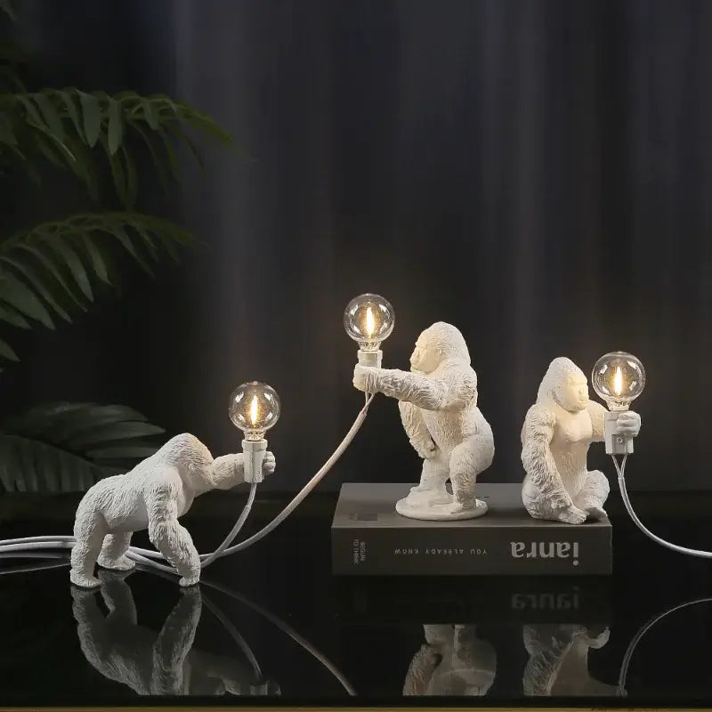 Modern black resin gorilla night light set with three white figurines holding lit Edison bulbs for decorbites gorilla night use