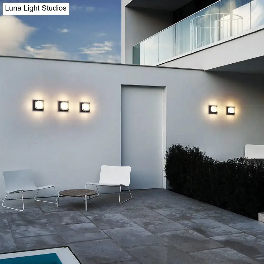 Modern black hexagonal square patio wall light with frosted glass and warm glowing square patio wall sconces