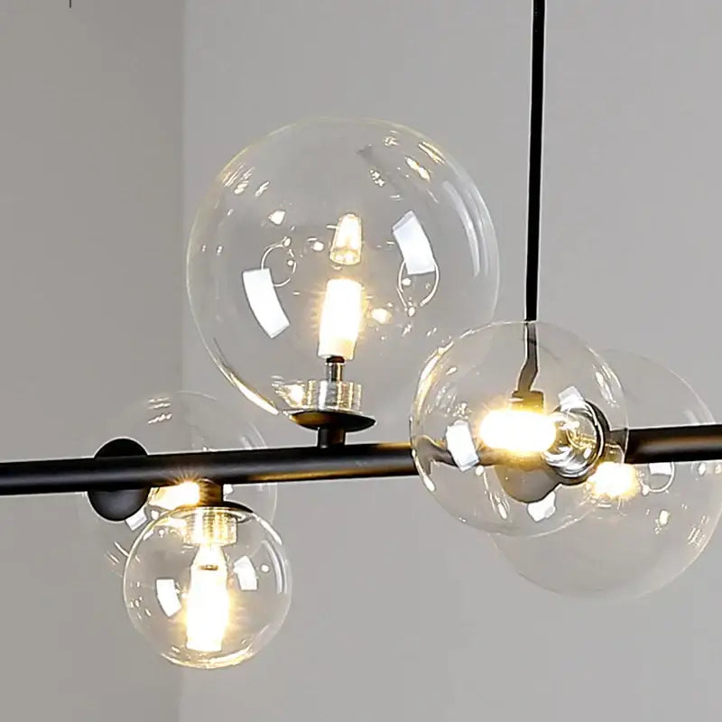 Modern black metal chandelier with clear glass globe shades and warm led bulbs.