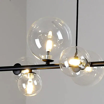 Modern black metal chandelier with clear glass globe shades and warm led bulbs.