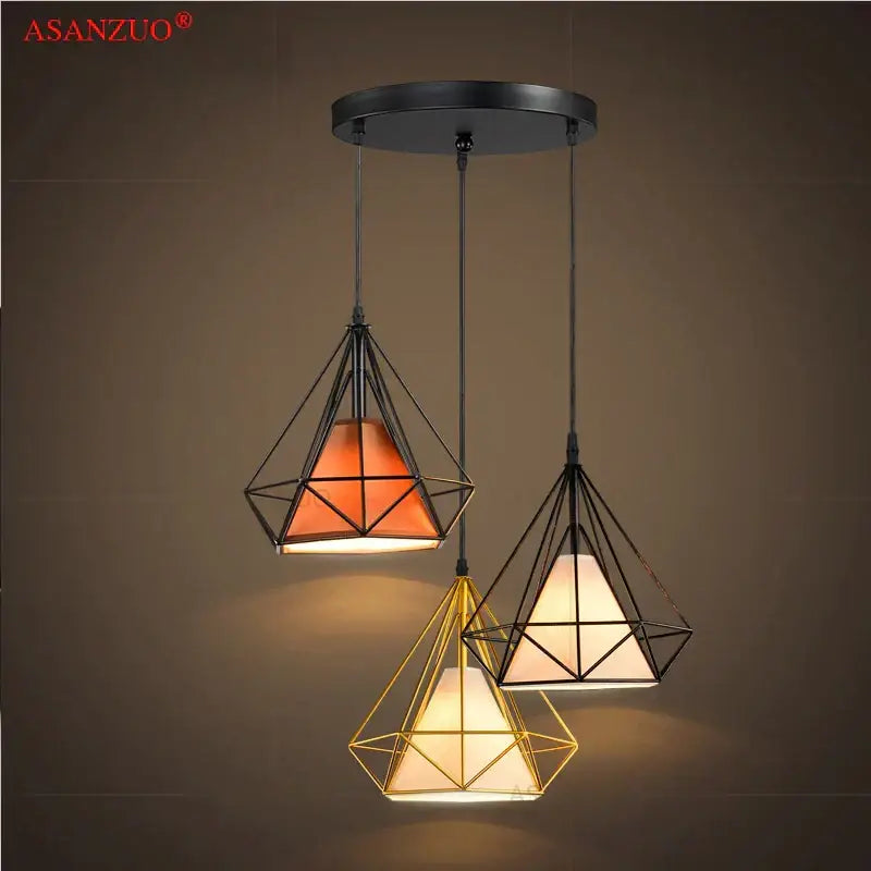Set of three modern dining room pendant lights with black and gold iron chassis ceiling frames and warm fabric shades