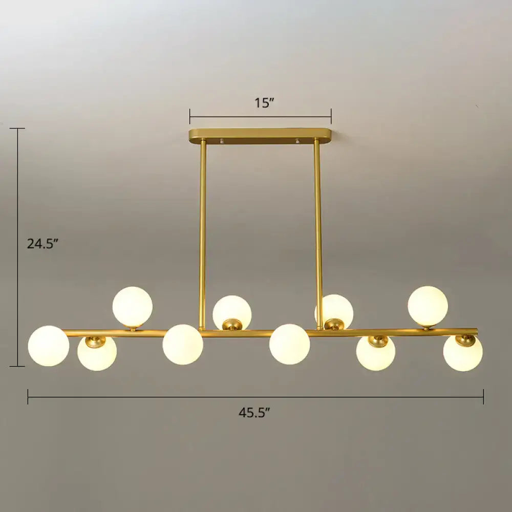 Gold-toned modern modo island ceiling light with nine frosted glass globes on horizontal bar for dining room use