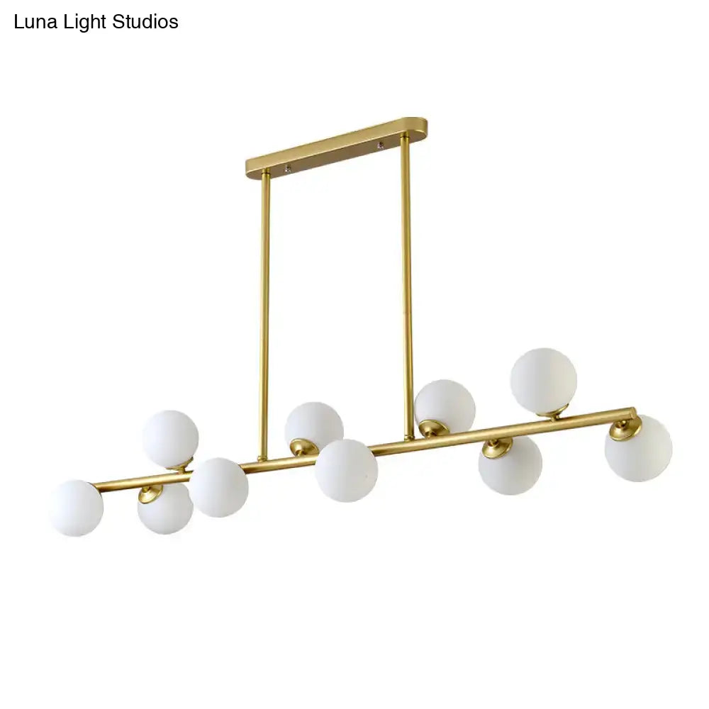 Modern gold-toned modo island ceiling light with nine frosted glass globe bulbs on a sleek rectangular mount for dining rooms