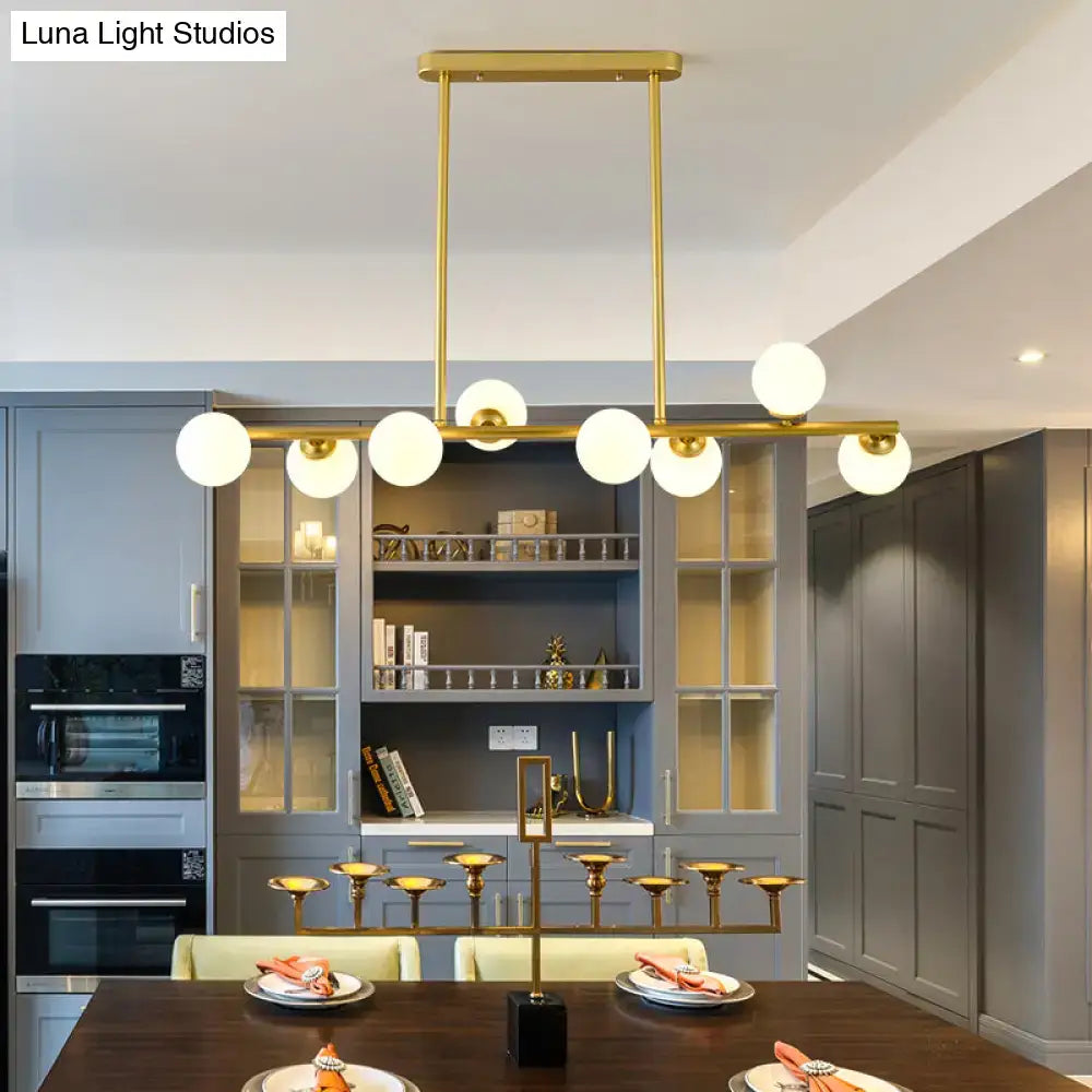 Gold-toned modern modo island ceiling light with spherical frosted glass shades for dining room illumination