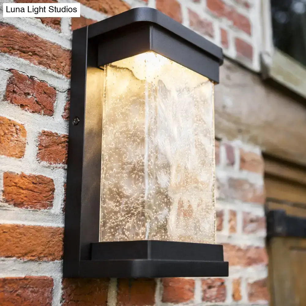 Modern black led outdoor wall sconce with textured translucent rippled glass cylinder diffusing warm light