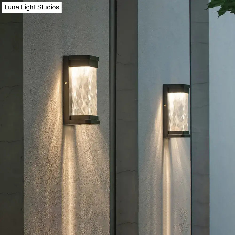 Modern black led outdoor wall sconce with rippled textured glass diffuser emitting warm light