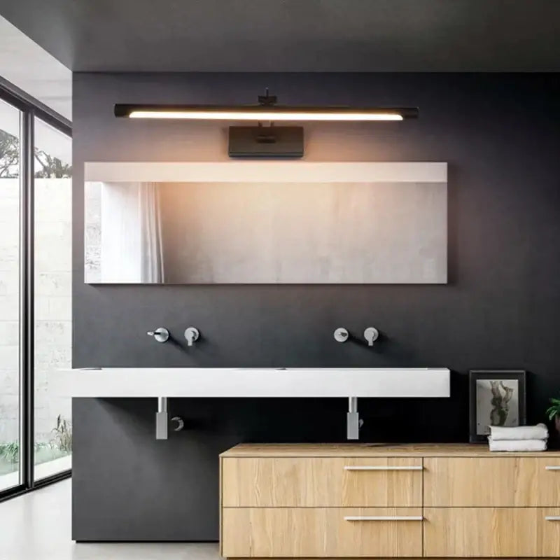 Modern black led vanity wall lamp with adjustable arm mounted above a frameless rectangular mirror on double sink vanity