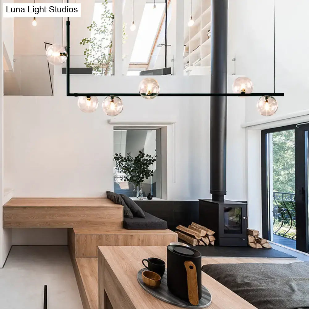 Modern black linear island pendant with glass shade shown above a black matte kettle with wooden handle on tray with matching mug