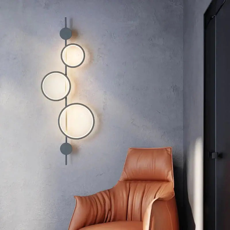 Modern black linear long led wall light with three circular illuminated shades and matte black metal accents for living room