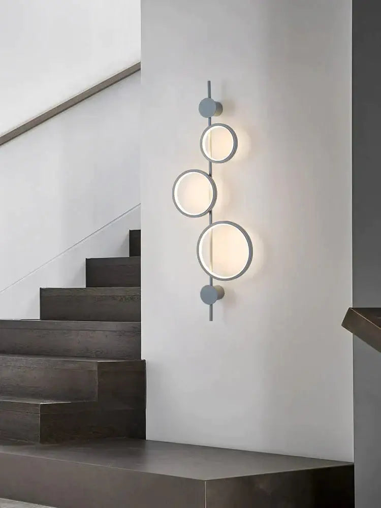 Modern black linear long led wall light with four matte gray circular fixtures emitting warm white light for living rooms