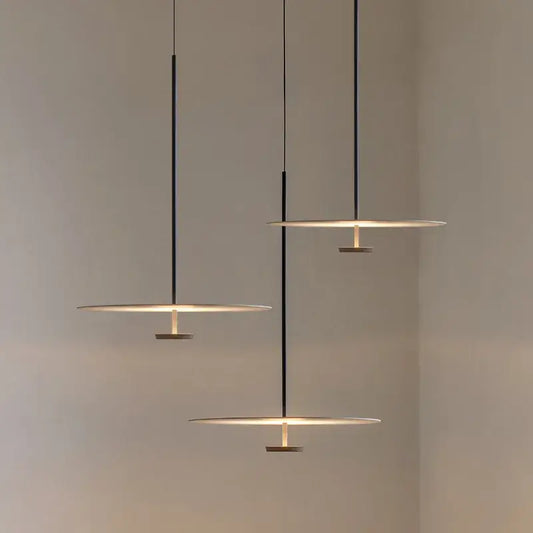 Modern black metal pendant light with minimalist circular disc shades emitting warm glow for dining room use