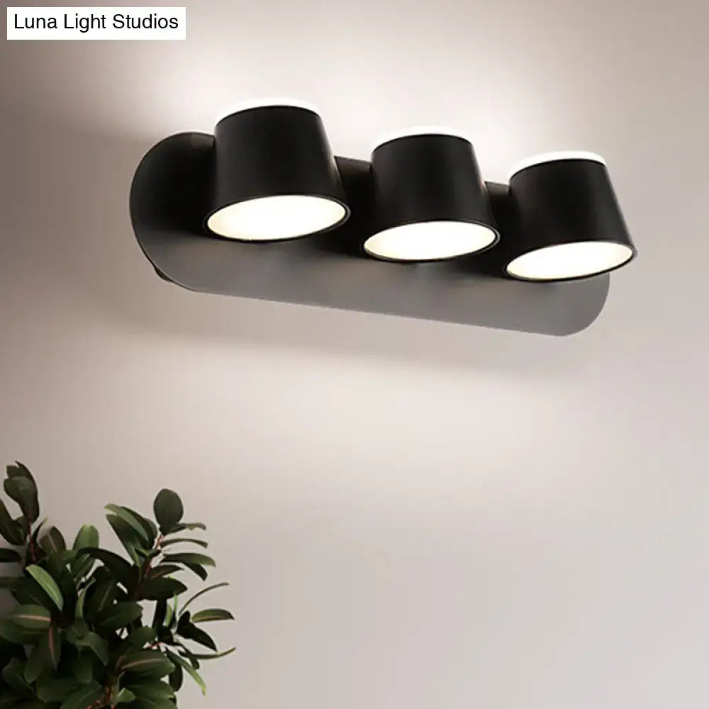 Modern black metal shade wall sconce with three cylindrical led heads and compact fixture width and shade height