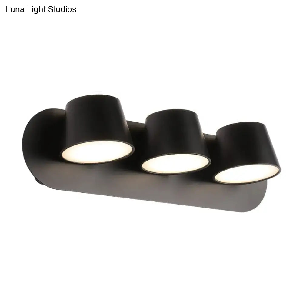 Modern black metal shade wall sconce fixture with three adjustable cylindrical lamps and compact fixture width for vanity use
