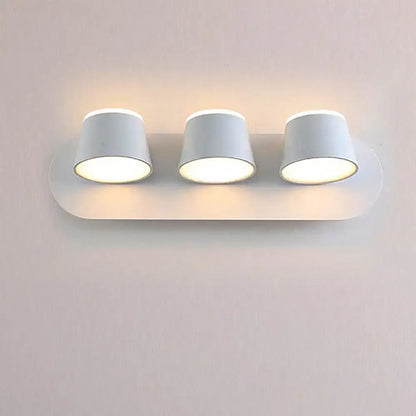 White minimalist metal shade wall sconce with three cylindrical led bulbs and compact fixture width for bedroom vanity