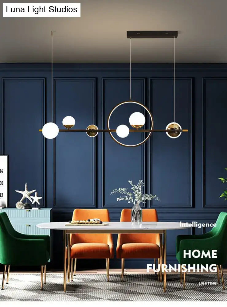 Modern black metal pendant light with spherical glass globes and brass frame for dining room illumination