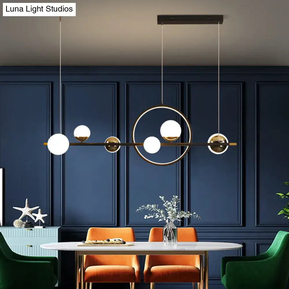 Modern black metal pendant light with spherical glass globes and brass frame for dining room illumination